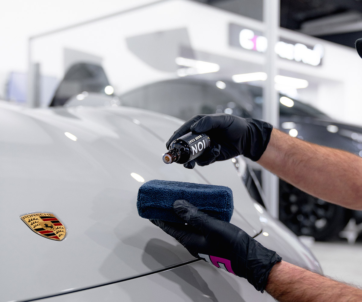 Ceramic Pro ION base coat being applied to a silver Porsche hood at Ceramic Pro Fuel House
