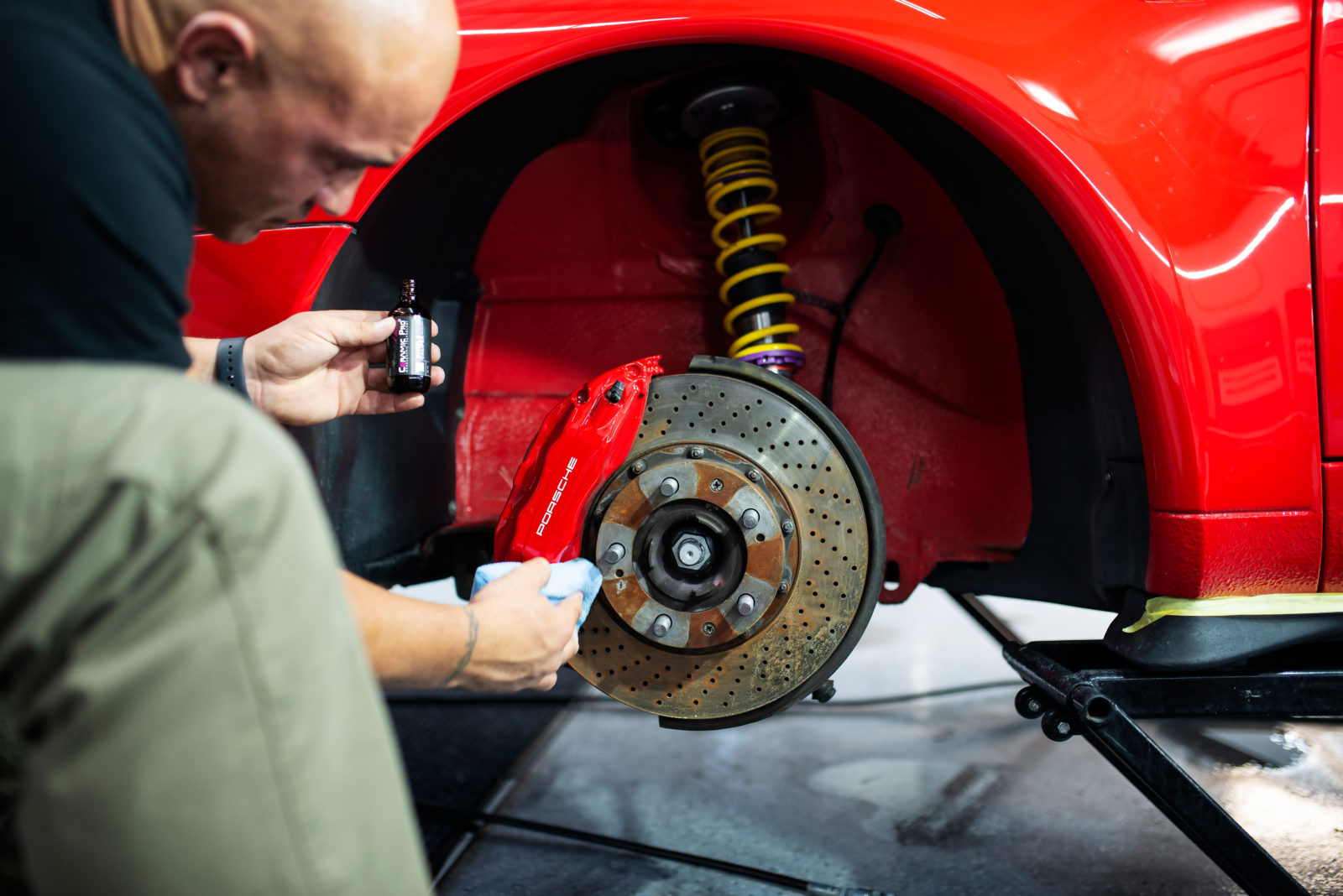 Ceramic Pro coating being applied to a red Porsche caliper at Ceramic Pro Fuel House